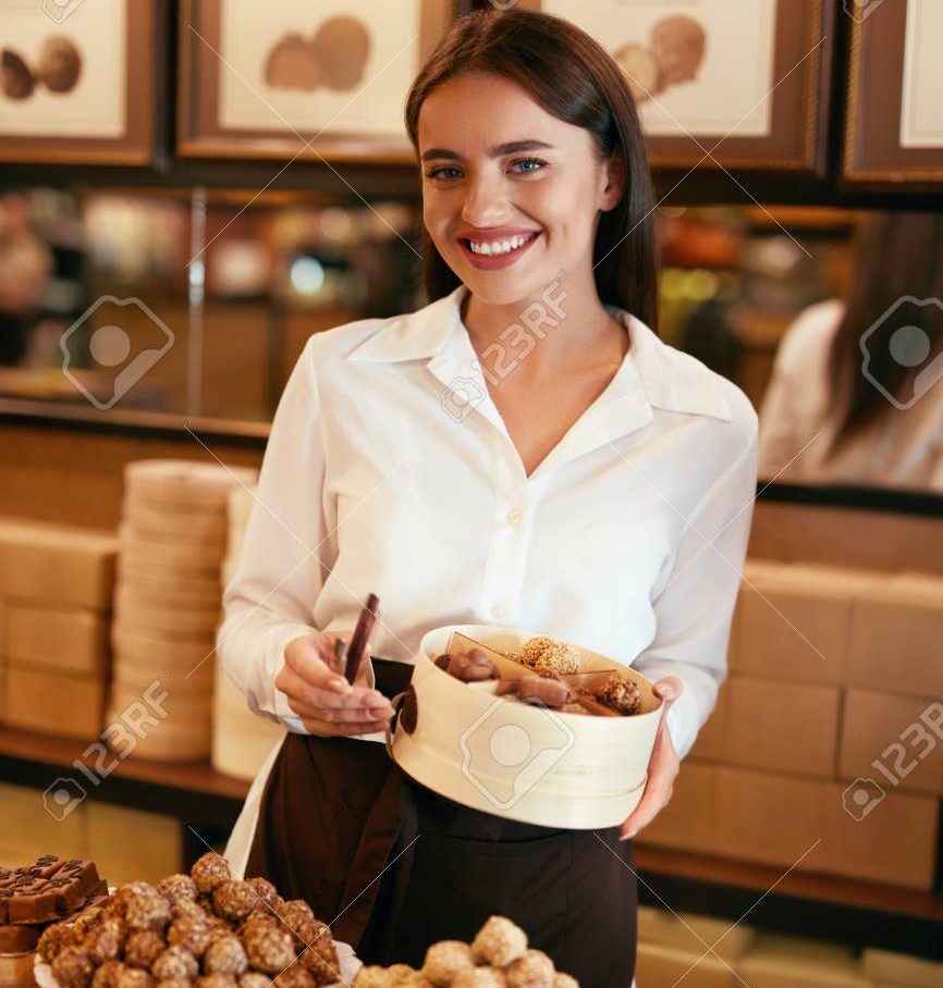 108328936 confectionery woman selling chocolate candies in store seller putting sweets and candies in box e1754273353104